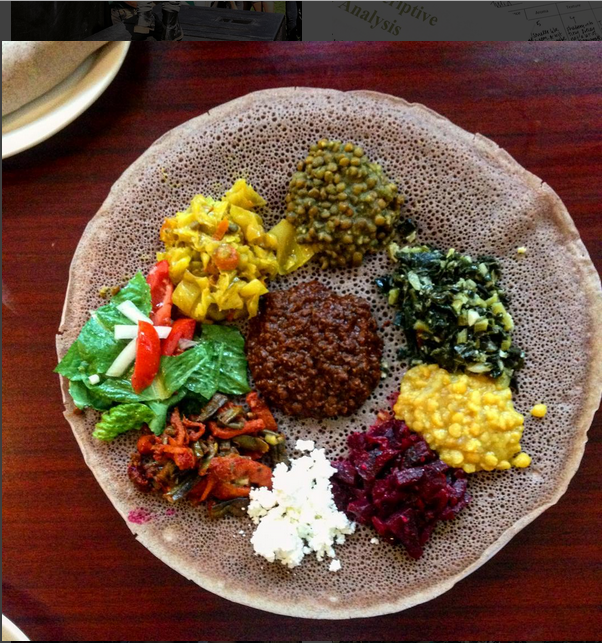 A round platter of colorful vegetarian stews served on injera.