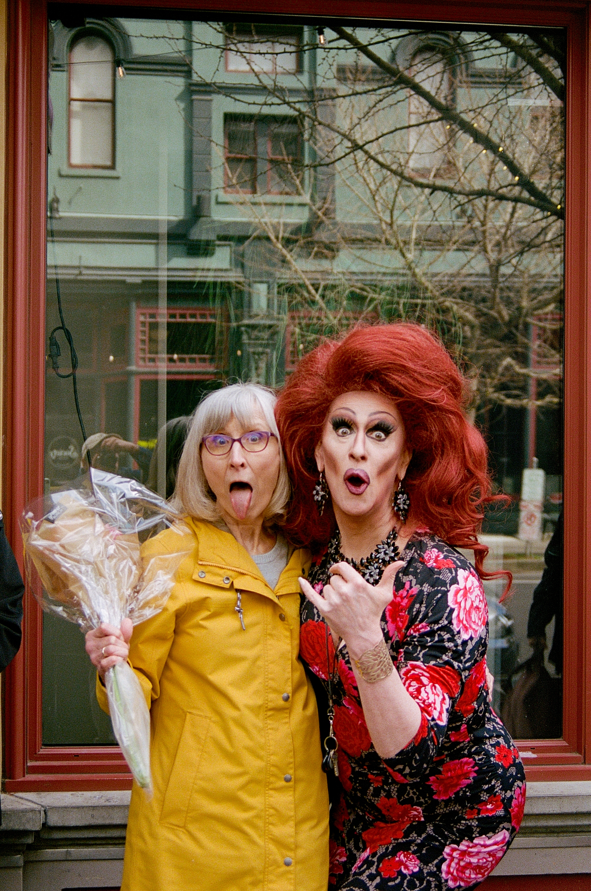 A drag queen poses with a patron holding a bouquet of flowers outside Darcelle XV.