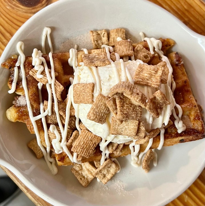A plate of waffles covered in Cinnamon Toast Crunch ceral and whipped cream.