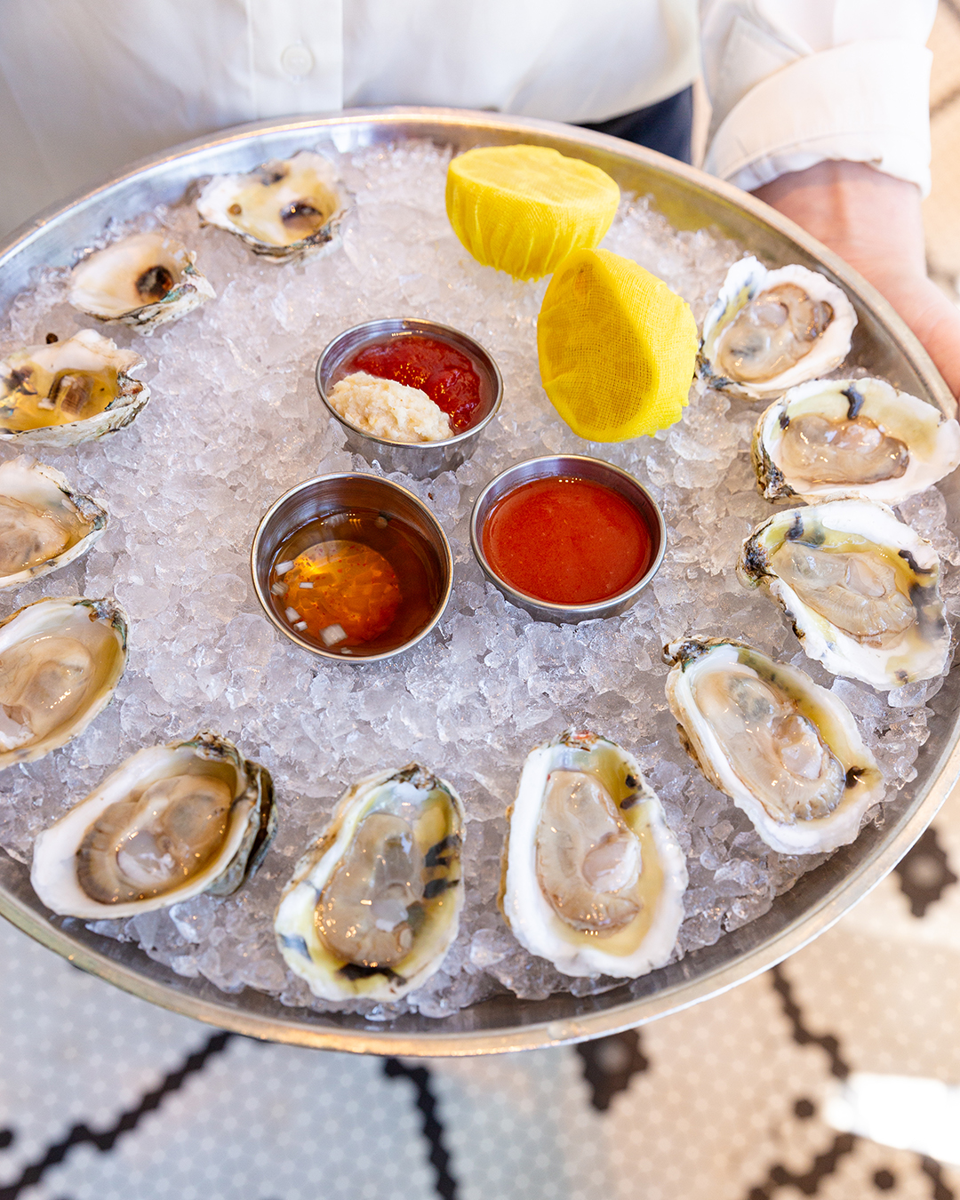 A platter of one dozen oysters on the half shelf over crushed ice with mignonette, horseradish sauce, and two lemon slices at the Select in Sandy Springs, GA.