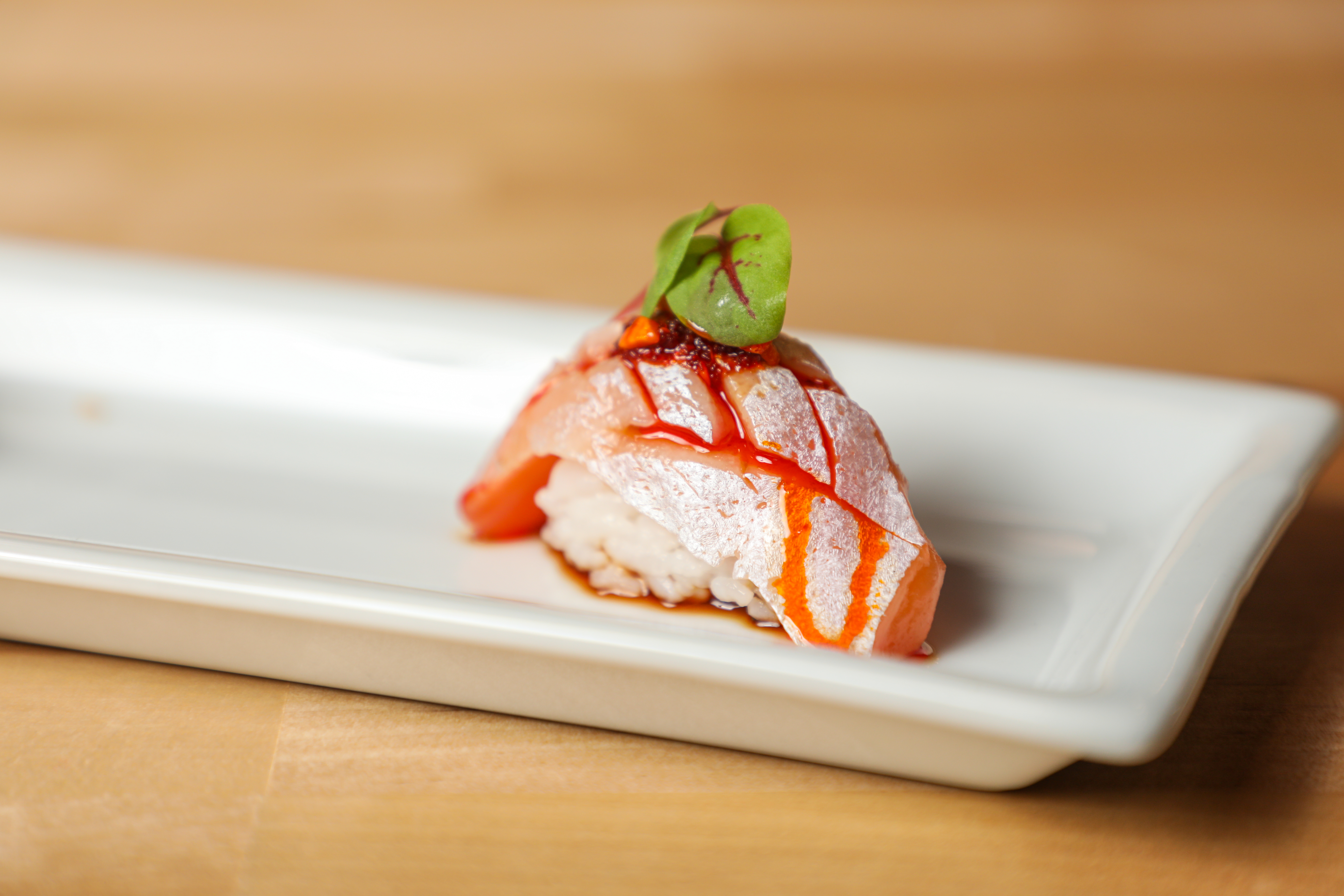 A piece of sake toro (aka salmon belly) topped with garlic almond chili oil.&nbsp;
