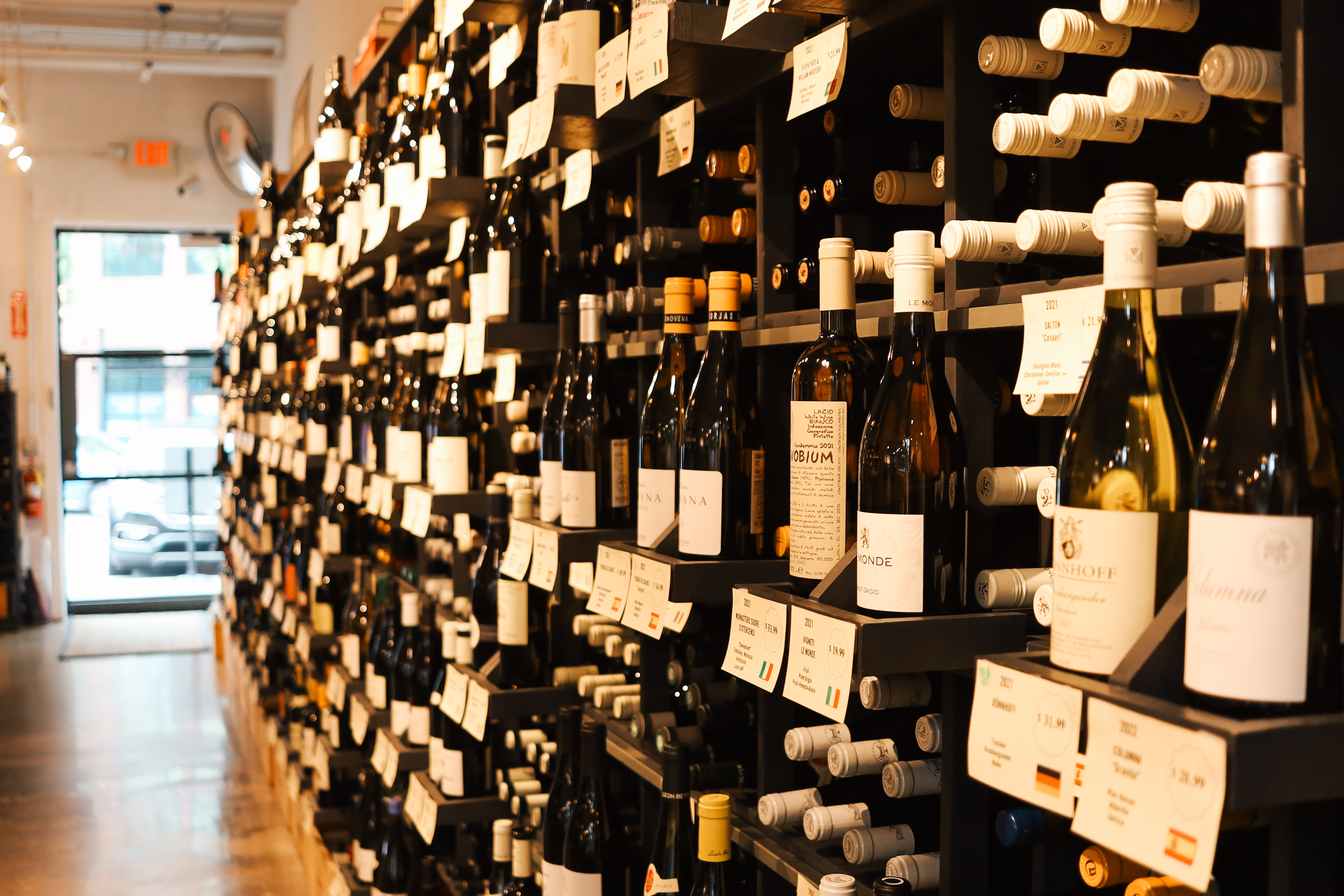 Rows of wine bottles in a shop with a few labels visible.