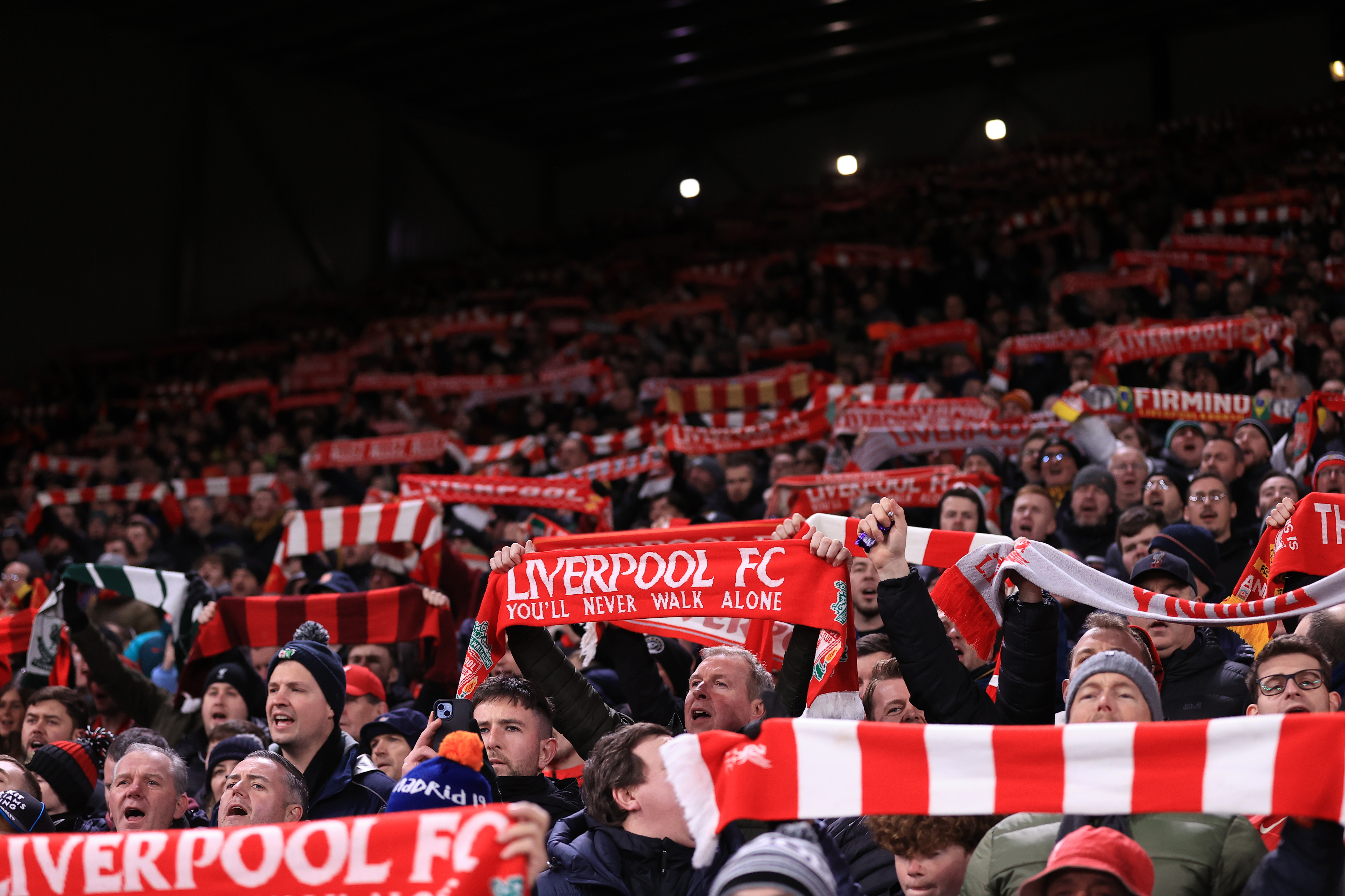 Liverpool fans hold their scarves aloft - Premier League