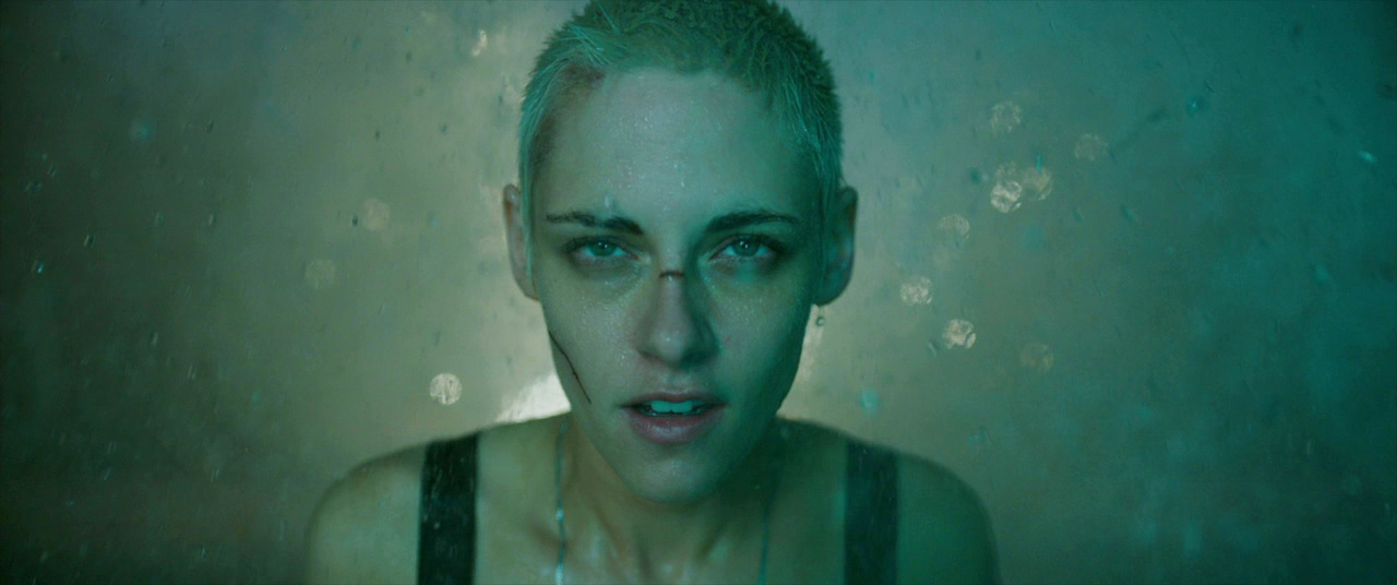 A woman with short blond hair staring forward drenched in water.