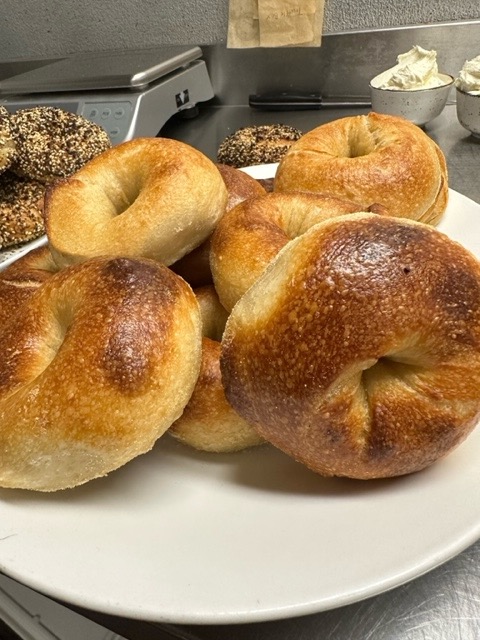 A pile of several blistery plain bagels.
