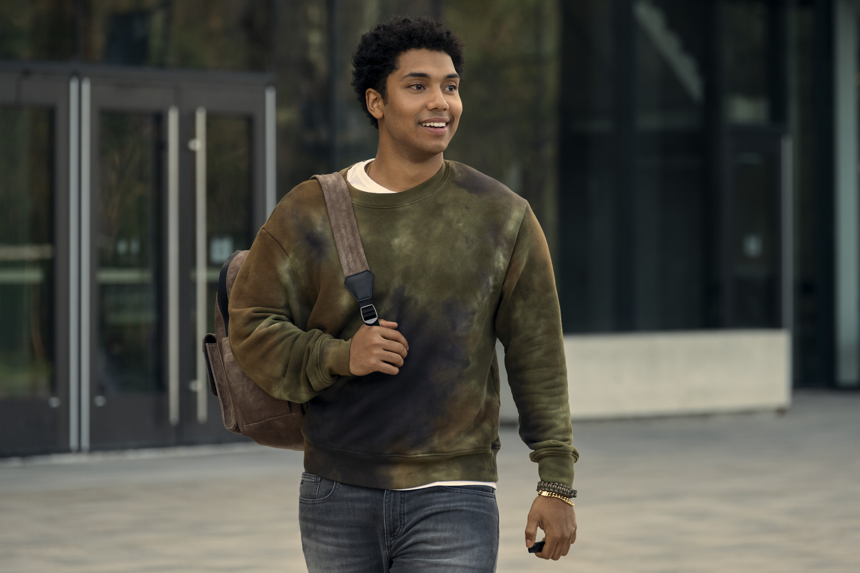 Godolkin student Andre (Chance Perdomo) cheerily walks out of a building with a bag hanging off his shoulder, unaware of the horrors that await him in the Prime Video series Gen V.