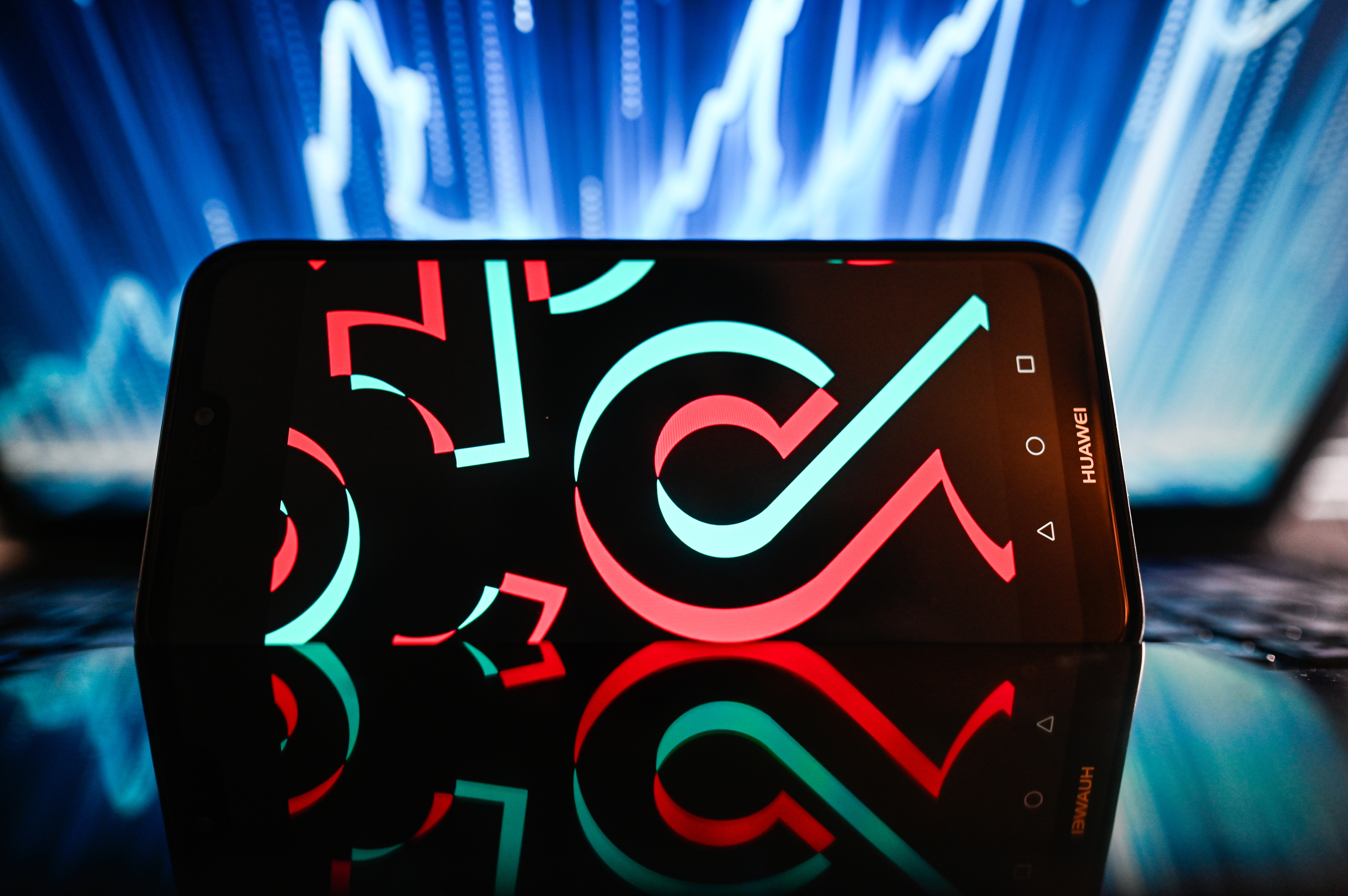 In this photo illustration, a TikTok logo is displayed on a smartphone with a line graph in the background.