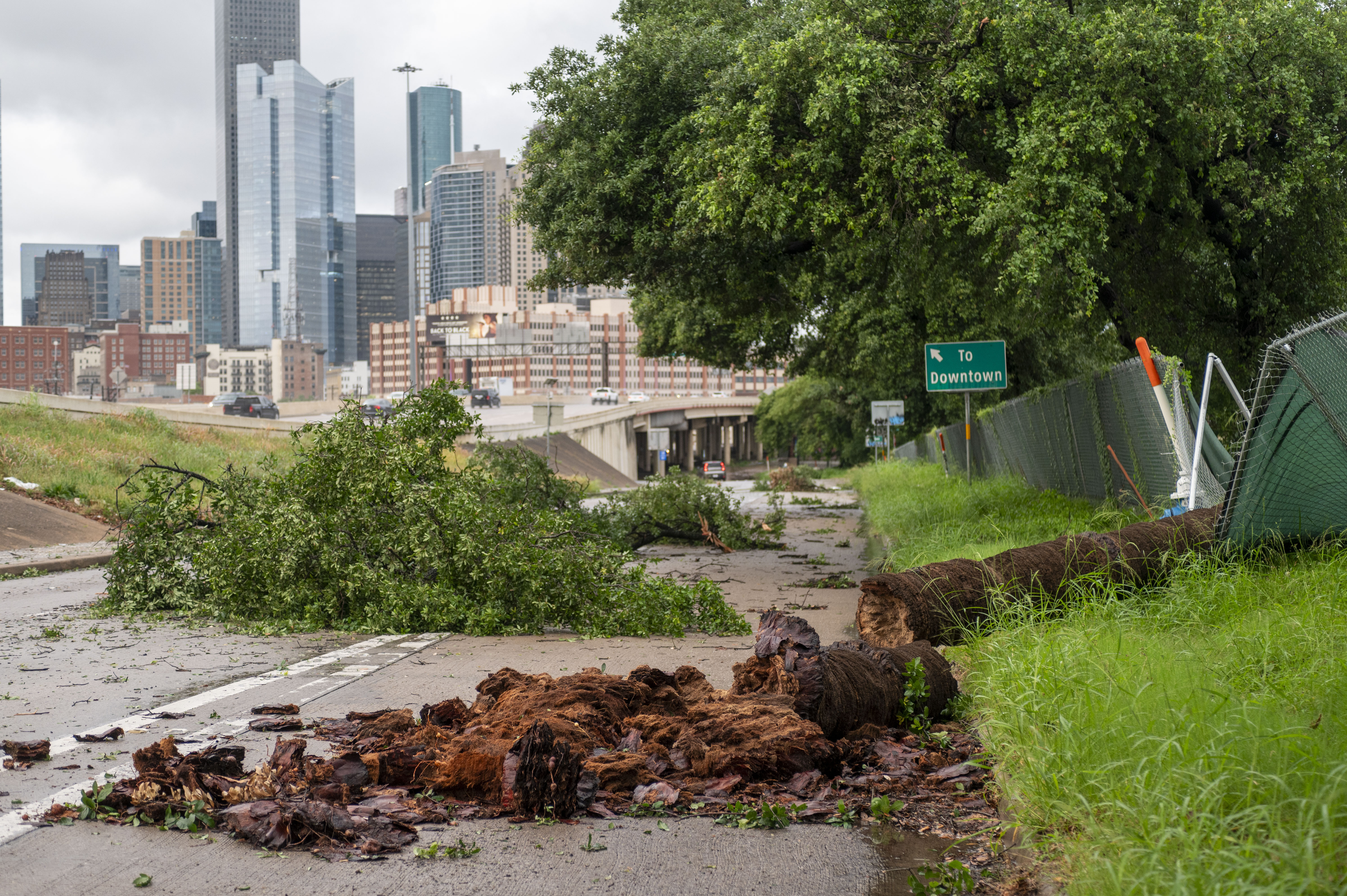 Debris is scattered across a slicked roadway with a view of downtown Houston high-rises in the background. 