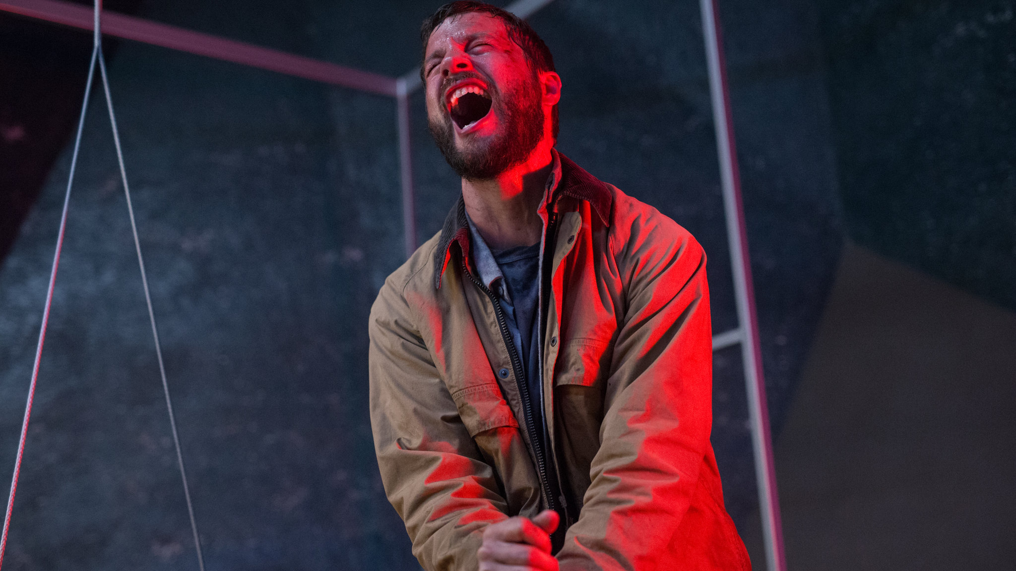 A man bathed in red lighting screaming in pain in Upgrade.