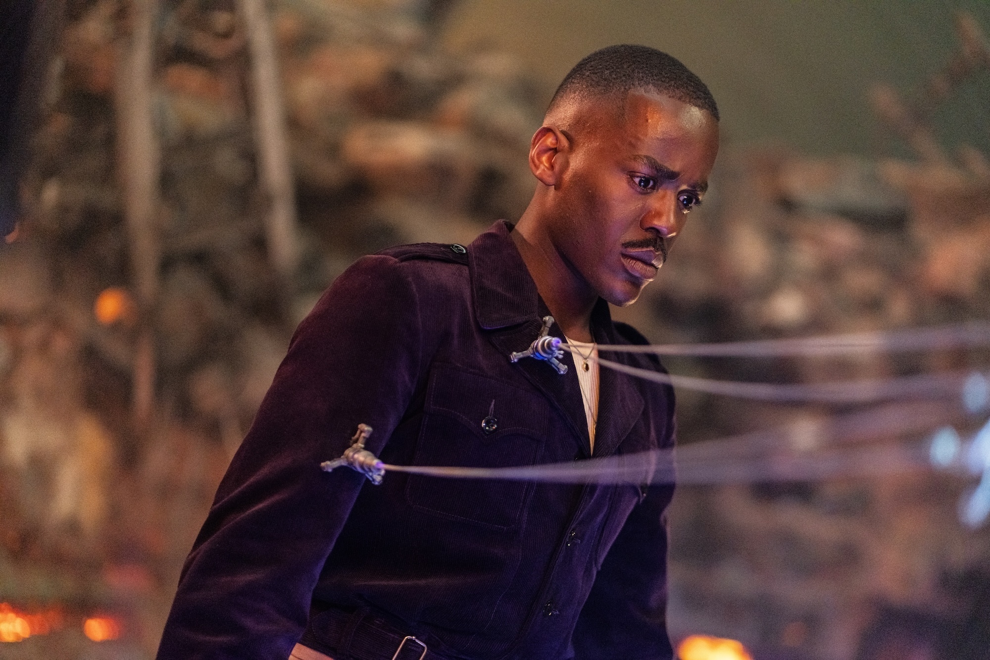 A close-up on the Fifteenth Doctor (Ncuti Gatwa) as he stands very still with cables attached to him in the episode “Boom.”
