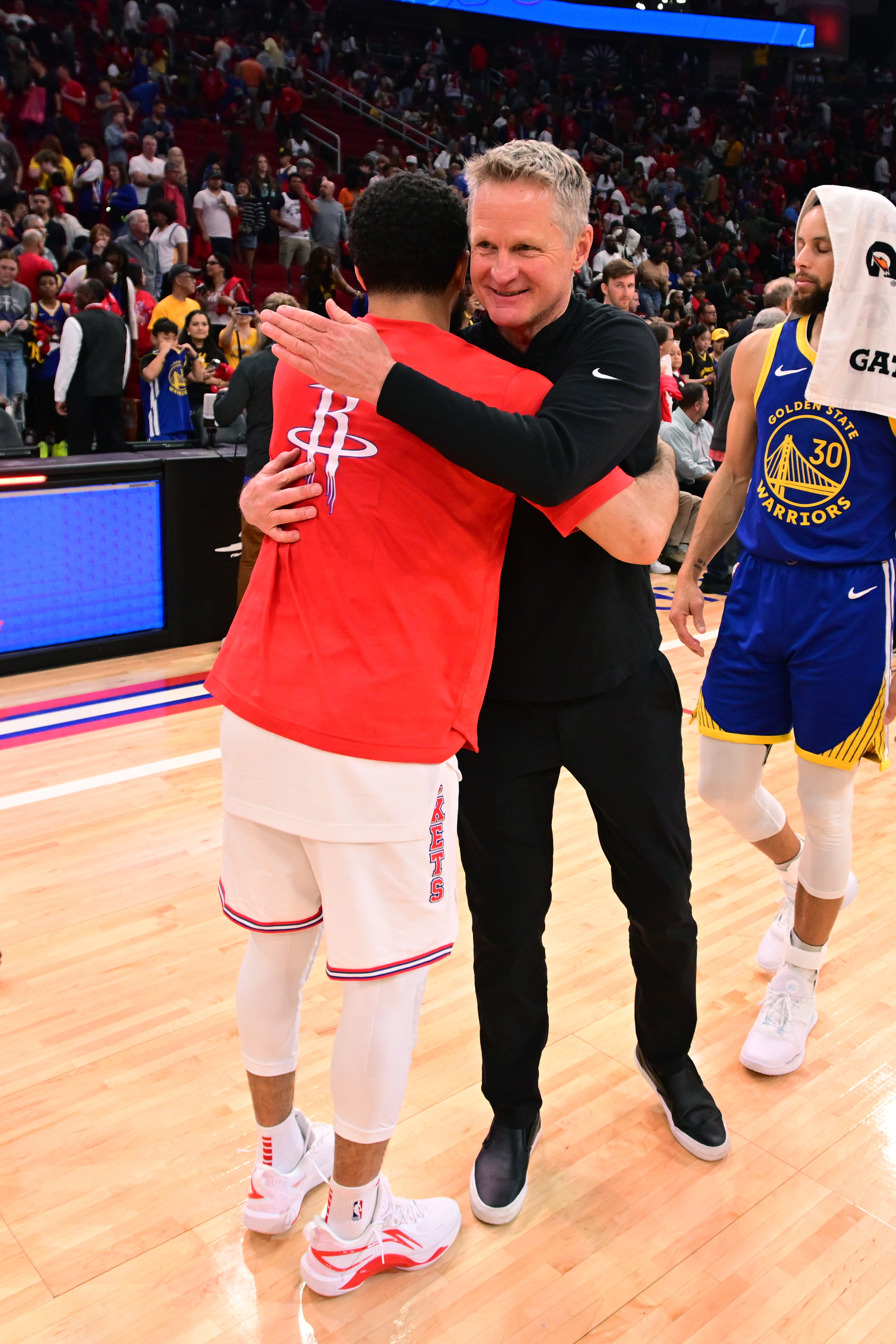 Steve Kerr hugging Fred VanVleet, with Steph Curry in the background. 