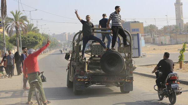 Палестинские бойцы едут на захваченной израильской военной машиной в секторе Газа
