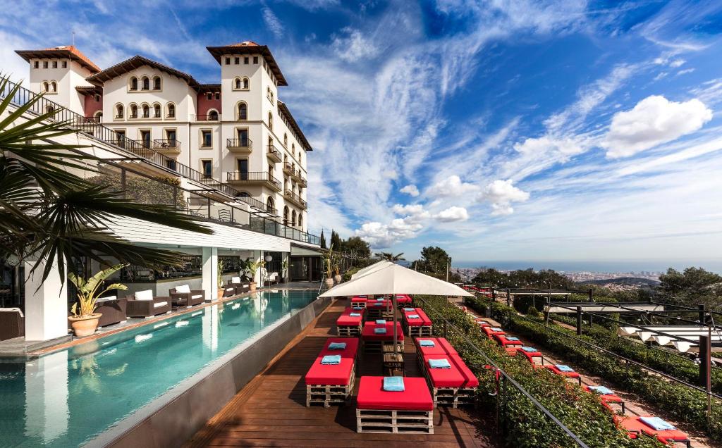hotelowy basen z czerwonymi krzesłami i parasolami w obiekcie Gran Hotel La Florida G.L Monumento w Barcelonie