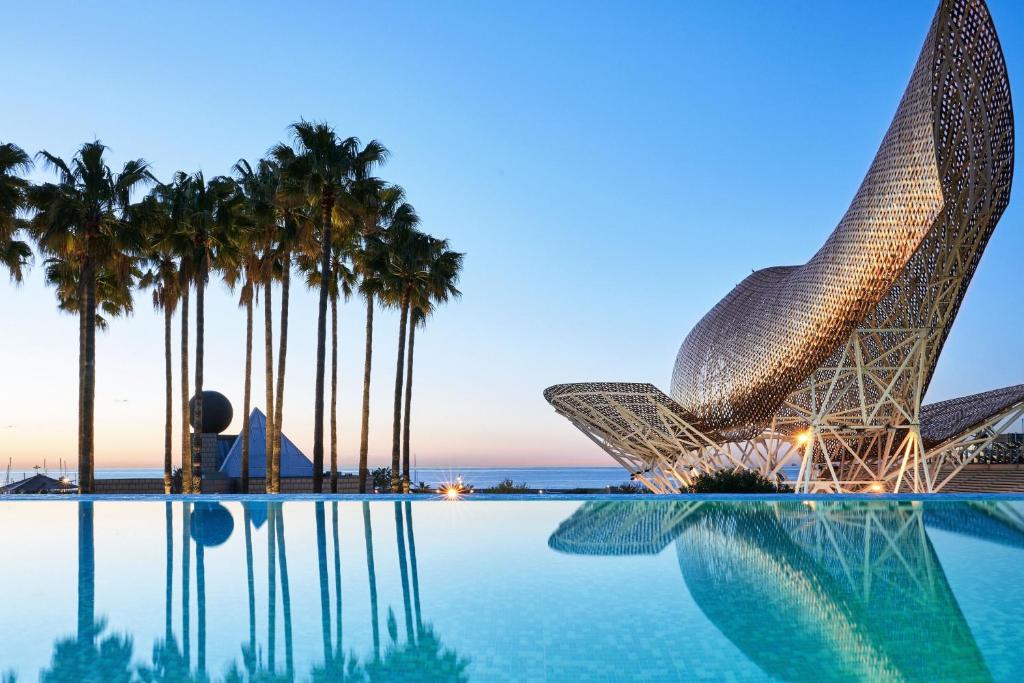 widok na ośrodek z basenem i palmami w obiekcie Hotel Arts Barcelona w Barcelonie
