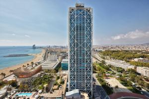 wysoki budynek obok plaży i oceanu w obiekcie Hotel Arts Barcelona w Barcelonie