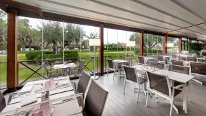 Hotel Spa Mediterraneo Park في روساس: مطعم بطاولات وكراسي ونوافذ