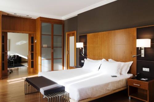 sypialnia z dużym białym łóżkiem z drewnianym zagłówkiem w obiekcie AC Hotel Almería by Marriott w mieście Almería