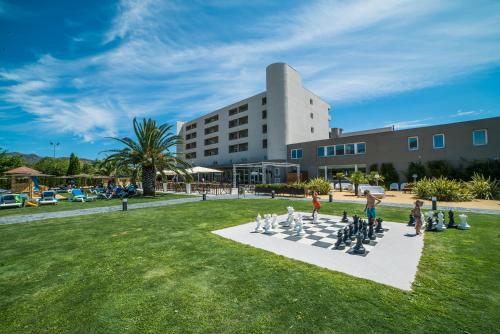 Hotel Spa Mediterraneo Park في روساس: مجموعة من الناس يلعبون الشطرنج أمام المبنى