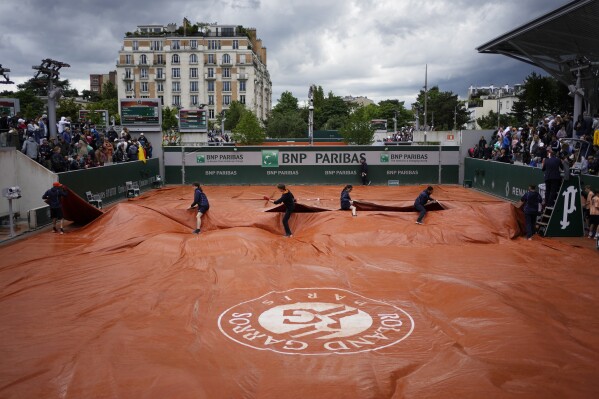 Stadium workers cover due to the rain during the French Open tennis tournament at the Roland Garros stadium in Paris, Thursday, May 30, 2024. (AP Photo/Thibault Camus)