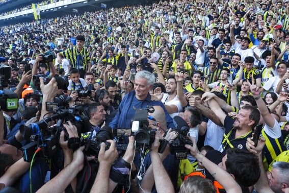 Portuguese soccer coach Jose Mourinho, center, poses for the media with supporters during his official presentation as Turkish's Fenerbahce new coach at Sukru Saracoglu stadium in Istanbul, Turkey, Sunday, June 2, 2024. Mourinho has signed a two-year contract with Fenerbahce. (AP Photo)