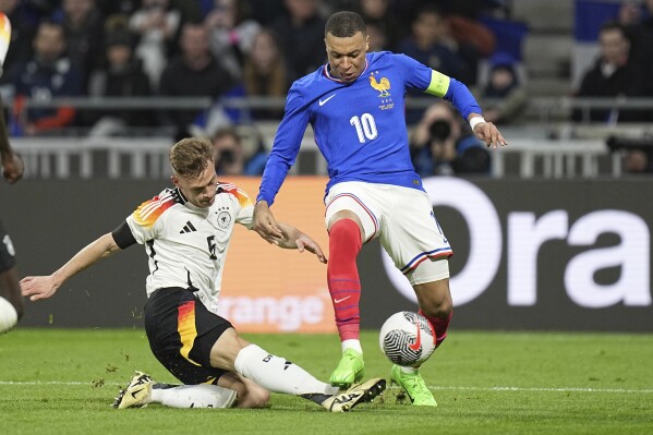 FILE - Germany's Joshua Kimmich, left, kicks the ball ahead of France's Kylian Mbappe during an international friendly soccer match between France and Germany at the Groupama stadium in Decines, near Lyon, central France, Saturday, March 23, 2024. France boasts one of the European Championship’s strongest attacks but it could be offset by a vulnerable defense and a dearth of leadership. While France looks solid in midfield and has Kylian Mbappé with Antoine Griezmann in attack, the defense could be a weak point. (AP Photo/Laurent Cipriani, File)