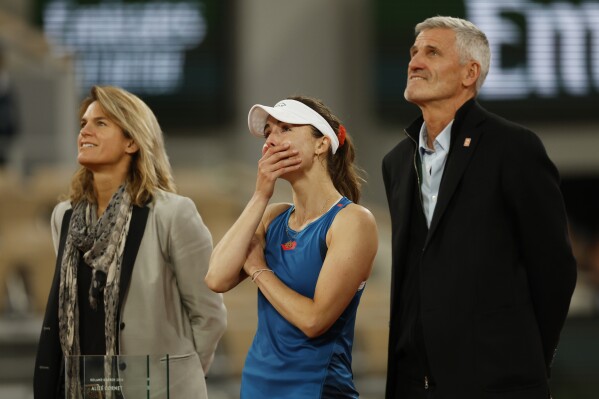 The tournament director and former French tennis star Amelie Mauresmo, left, and Gilles Moretton, head of the French Tennis Federation, right, greet France's Alize Cornet after her first round match of the French Open tennis tournament against China's Zheng Qinwen, at the Roland Garros stadium in Paris, Tuesday, May 28, 2024. (AP Photo/Jean-Francois Badias)