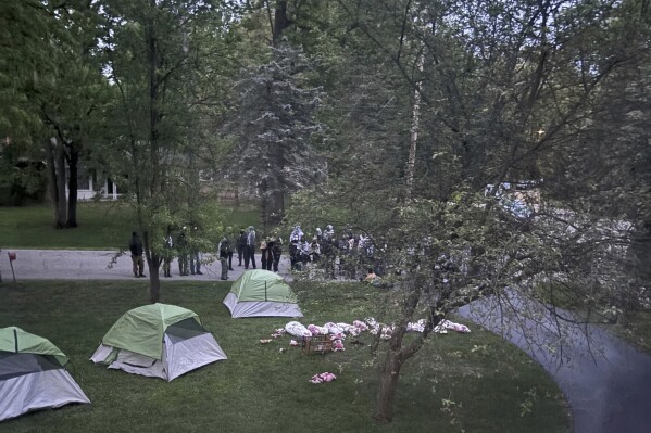 This photo provided by Sarah Hubbard shows pro-Palestinian protesters in Okemos, Mich., demonstrating outside the home of Sarah Hubbard, the chair of the University of Michigan's governing board, on Wednesday, May 15, 2024. They set up tents and placed fake bloody corpses on her lawn. They want the university to get rid of any investments in companies connected to Israel. (Sarah Hubbard via AP)