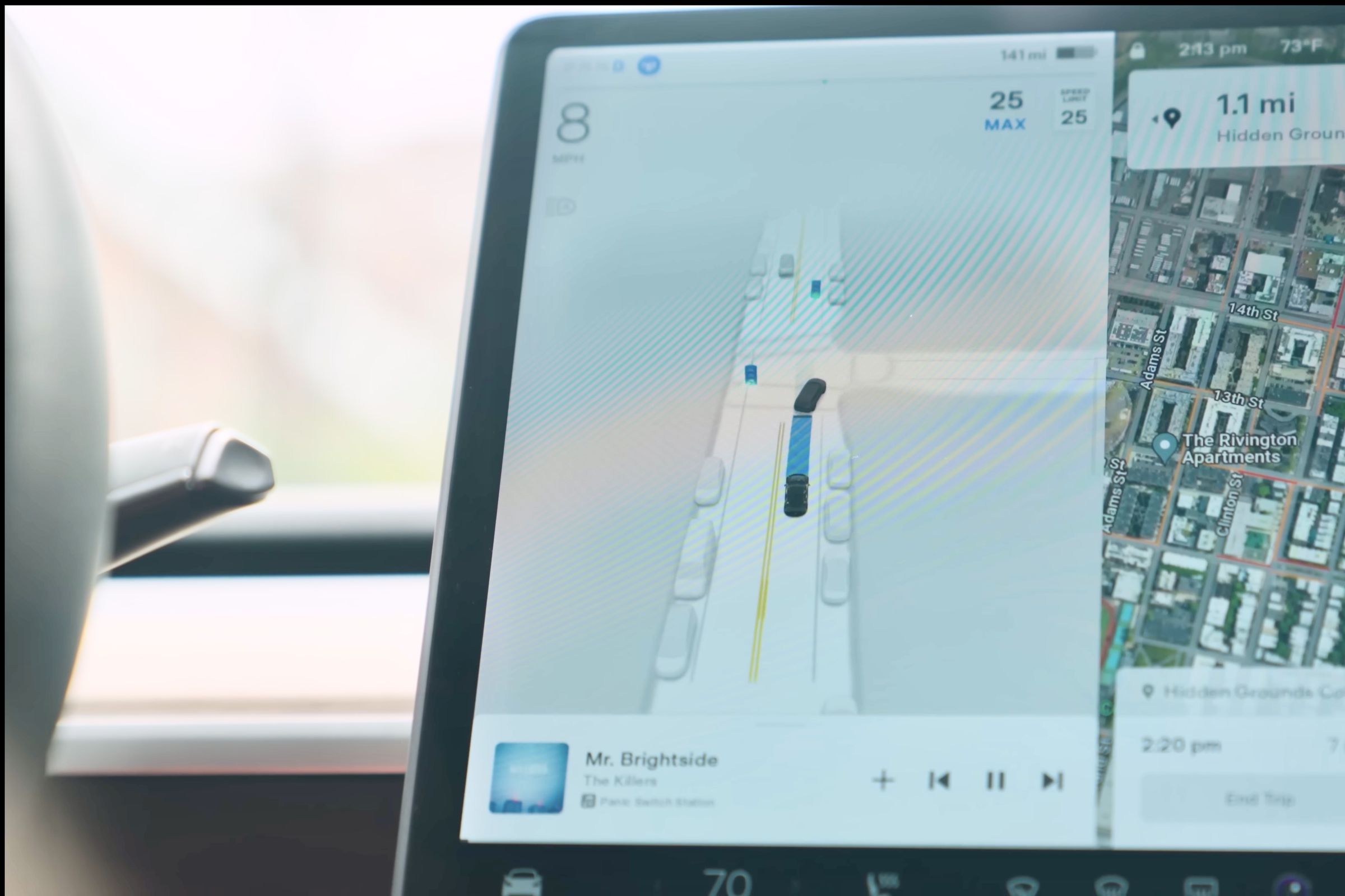 Left side of Tesla Model 3 main screen showing a computer-generated image of an intersection with cars parked on the sides and the Model 3 following another car