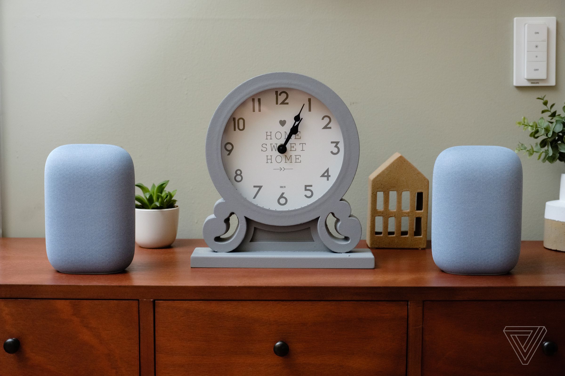 A picture of two Google Nest Audio speakers sitting on a piece of furniture.