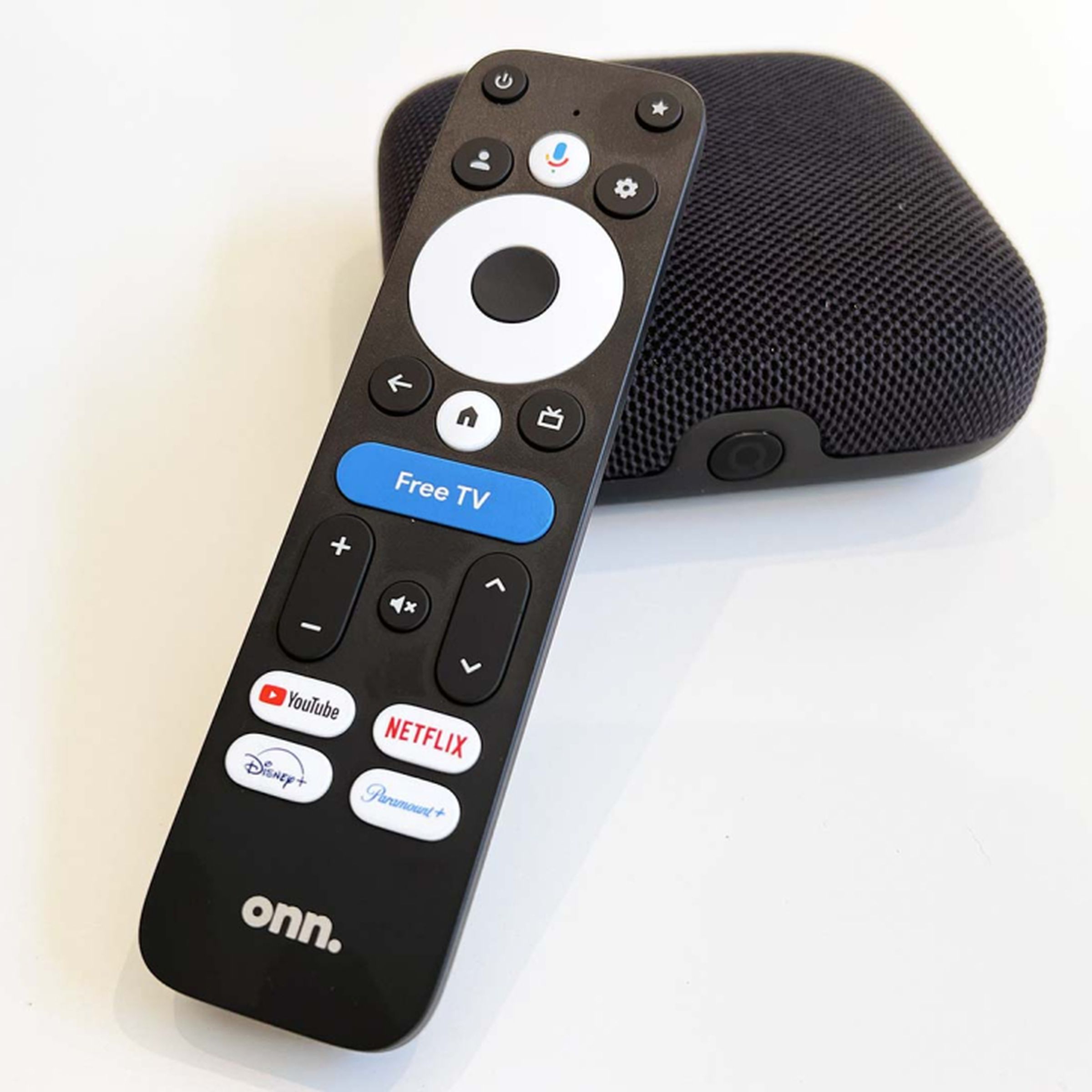 onn branded remote sitting on to of a square streaming box with a mesh fabric