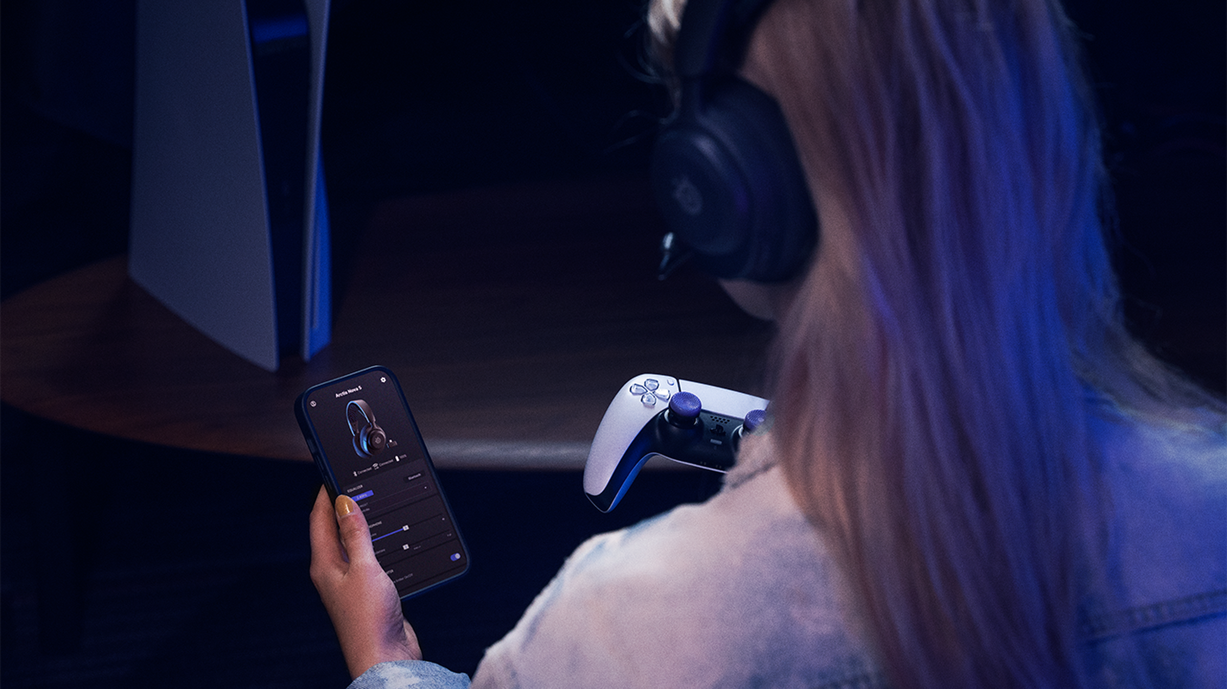 Someone using both the SteelSeries Arctis Nova 5 headset and it’s companion mobile app.