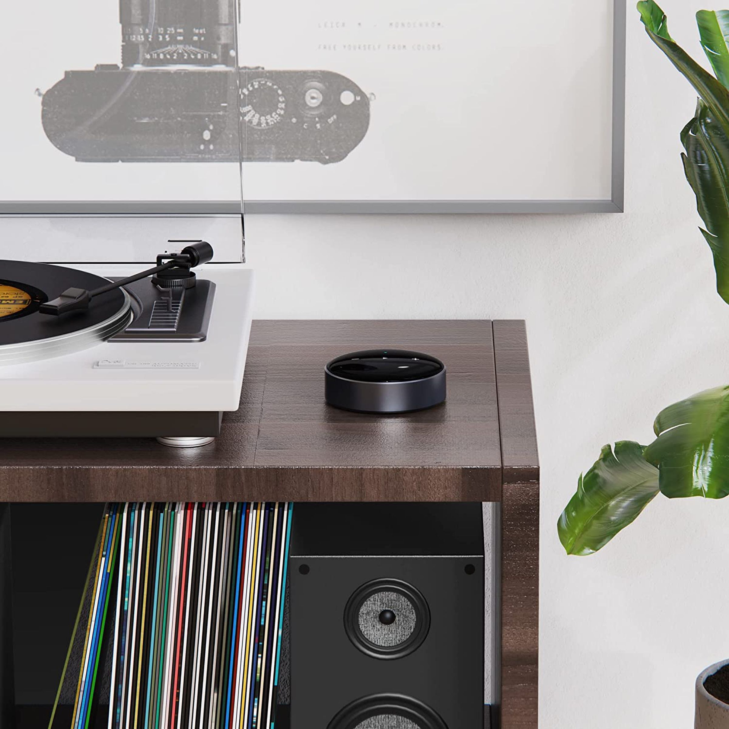 A WiiM Mini sitting on a wood credenza next to a turntable.