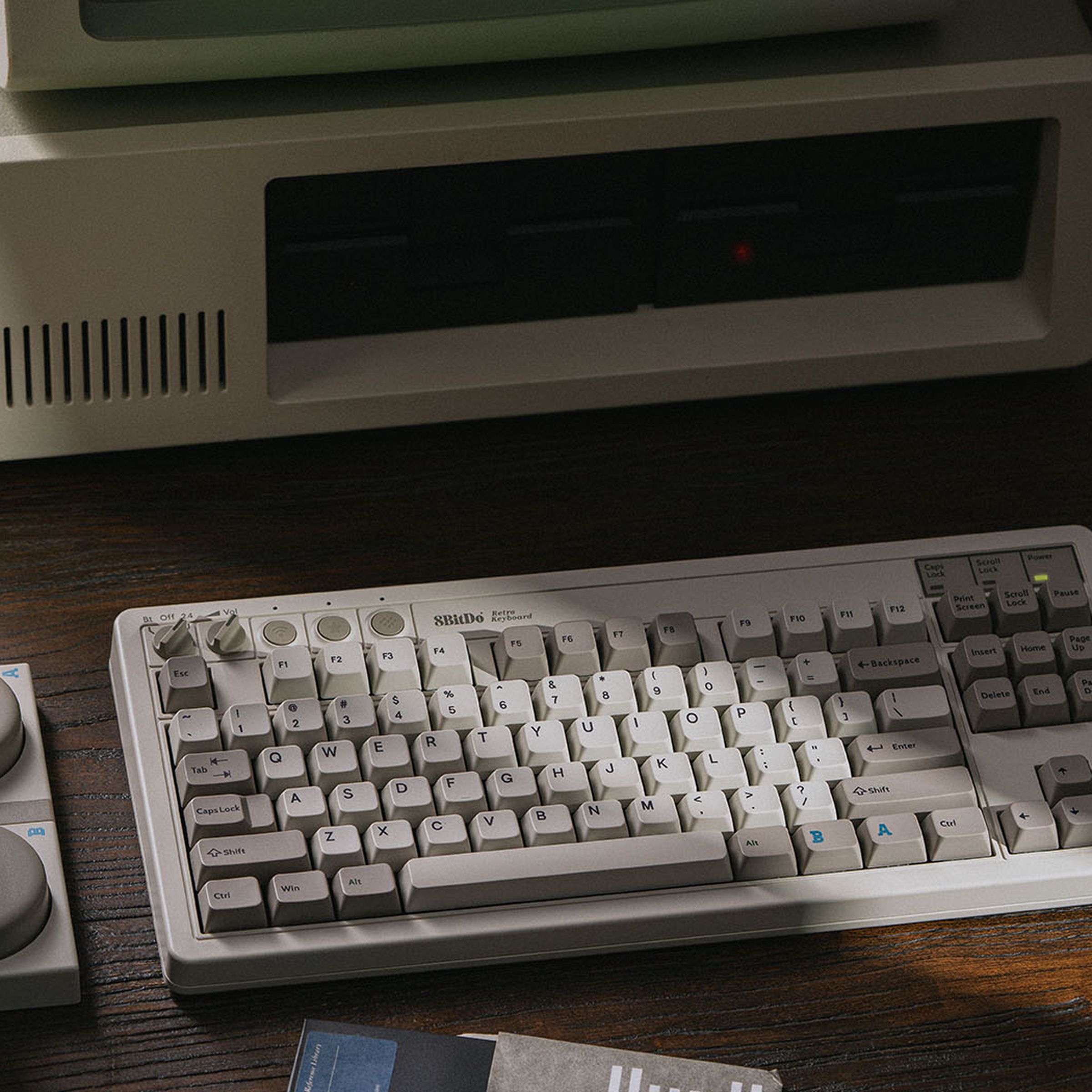8BitDo’s M Edition mechanical keyboard on a desk alongside its macro buttons, in front of a vintage IBM computer.