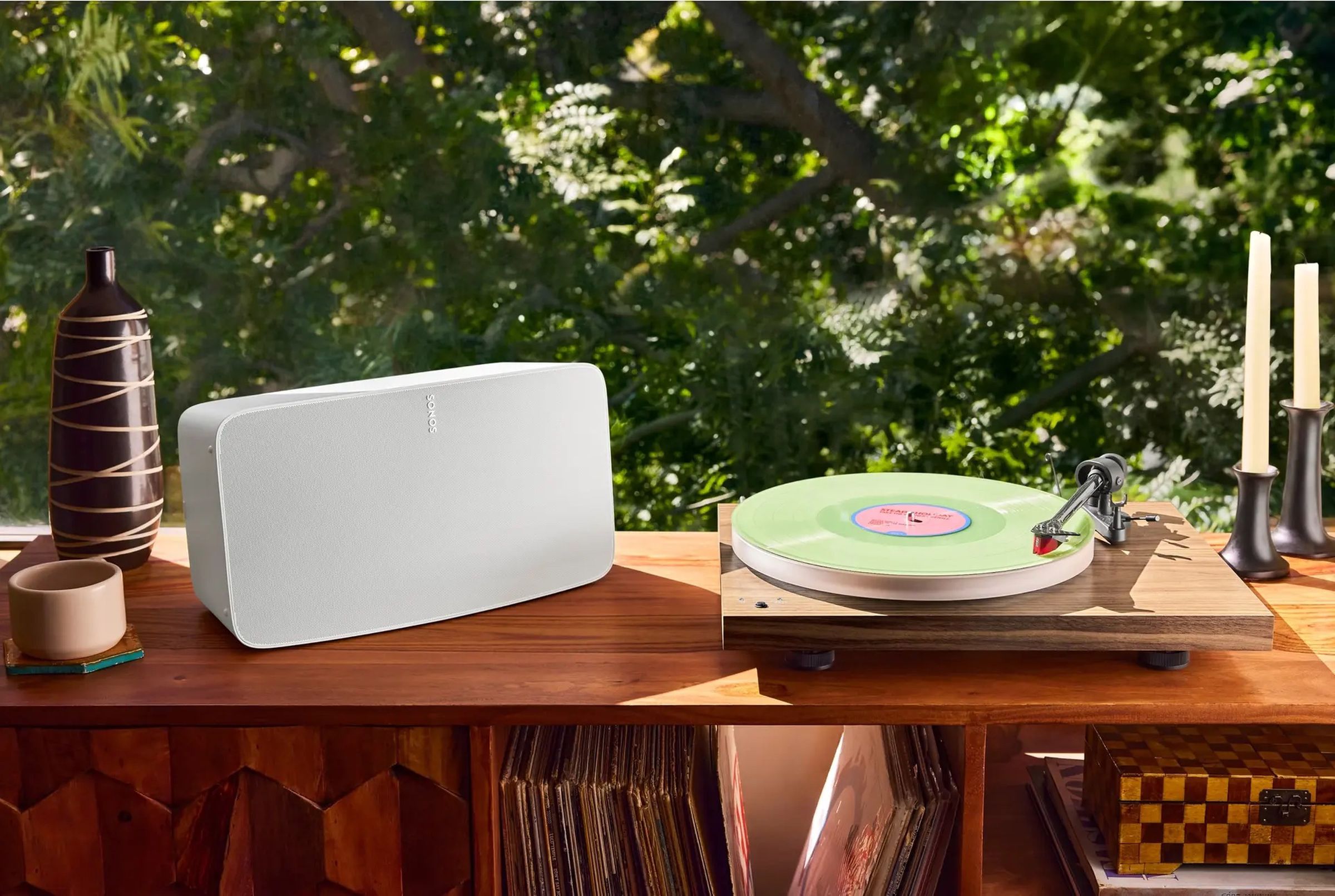 A photo of a Sonos Five next to a record player on a wooden table.