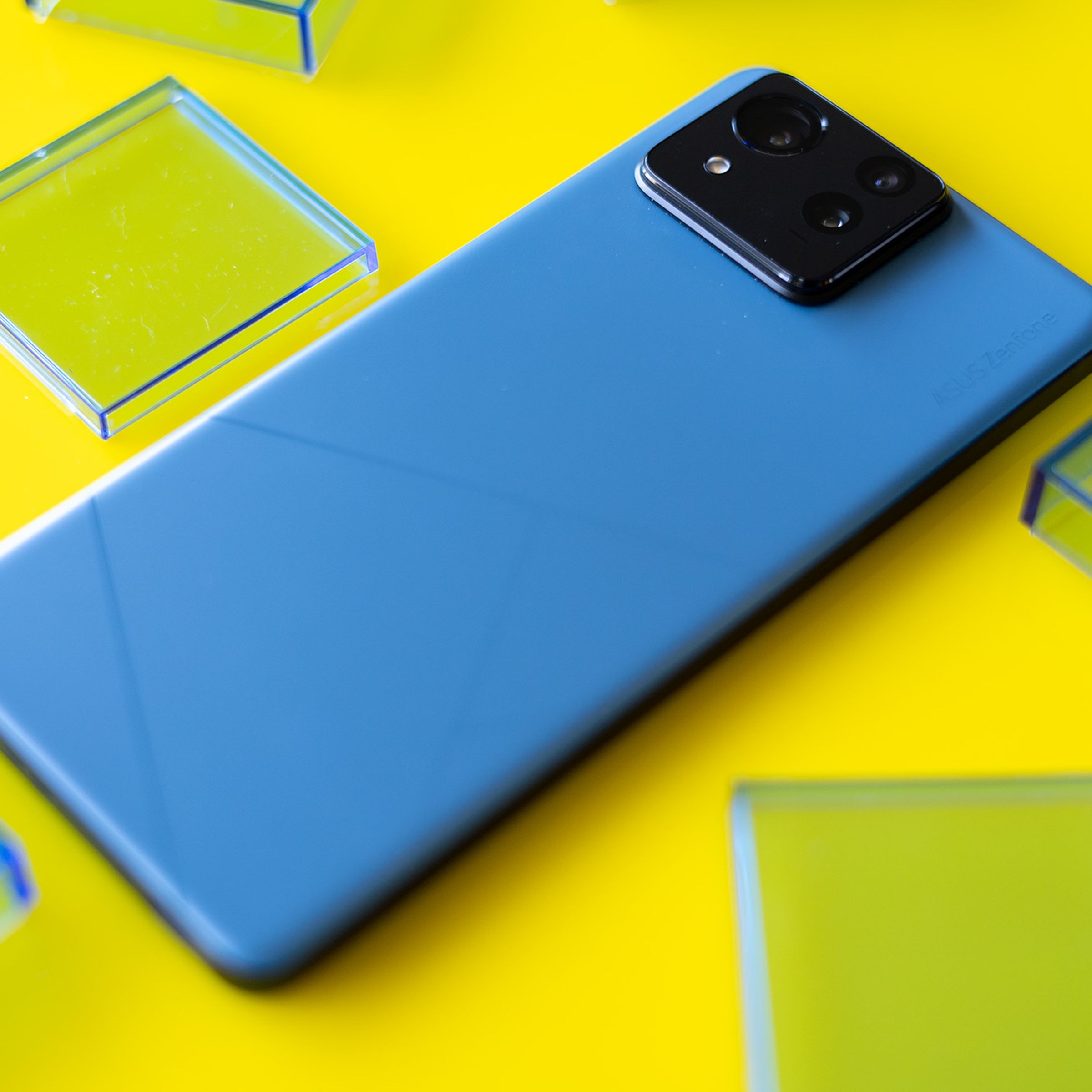 Asus Zenfone 11 Ultra on a yellow background surrounded by blue translucent squares.