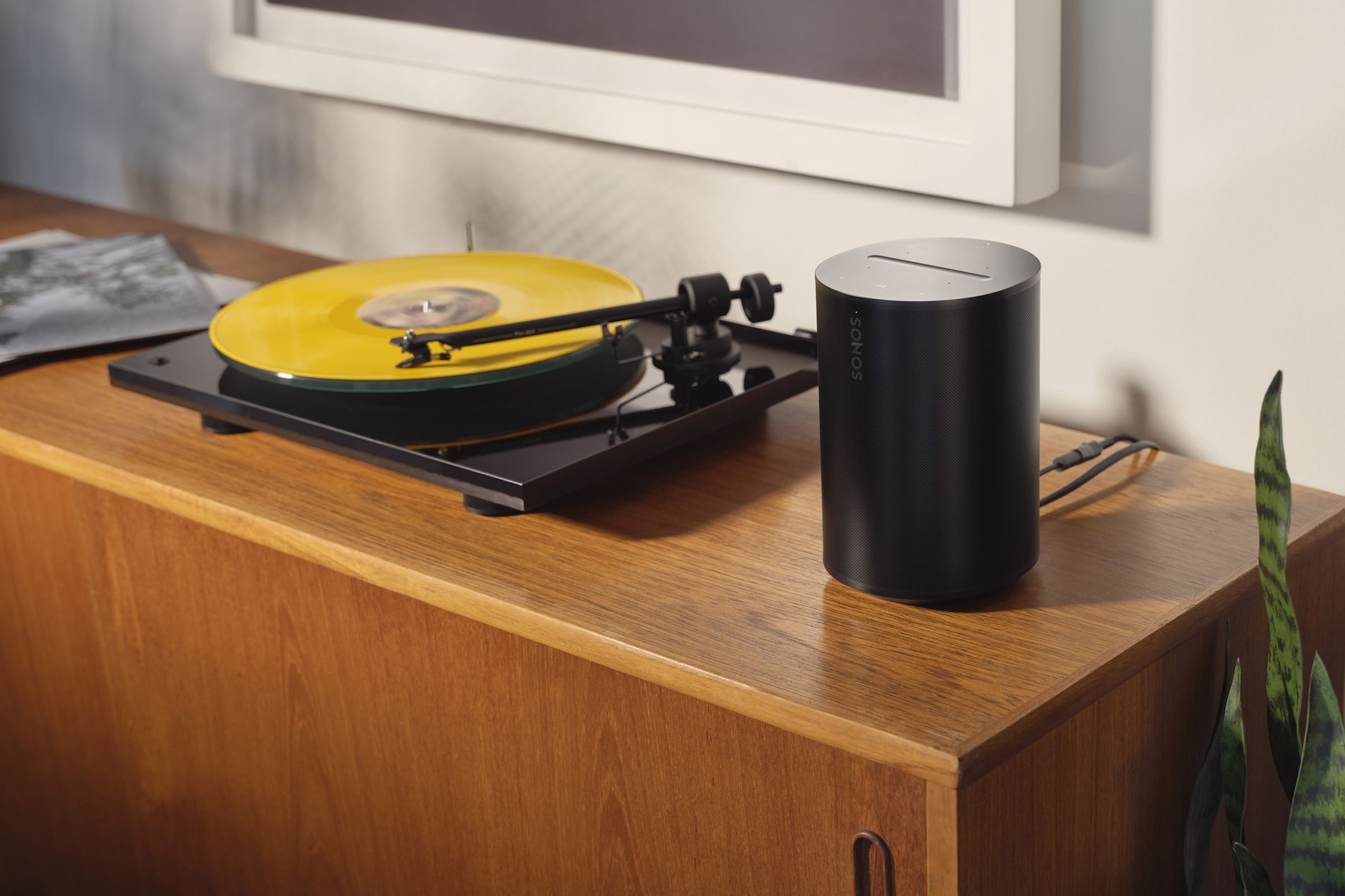 A photo of a Sonos Era 100 beside a turntable.