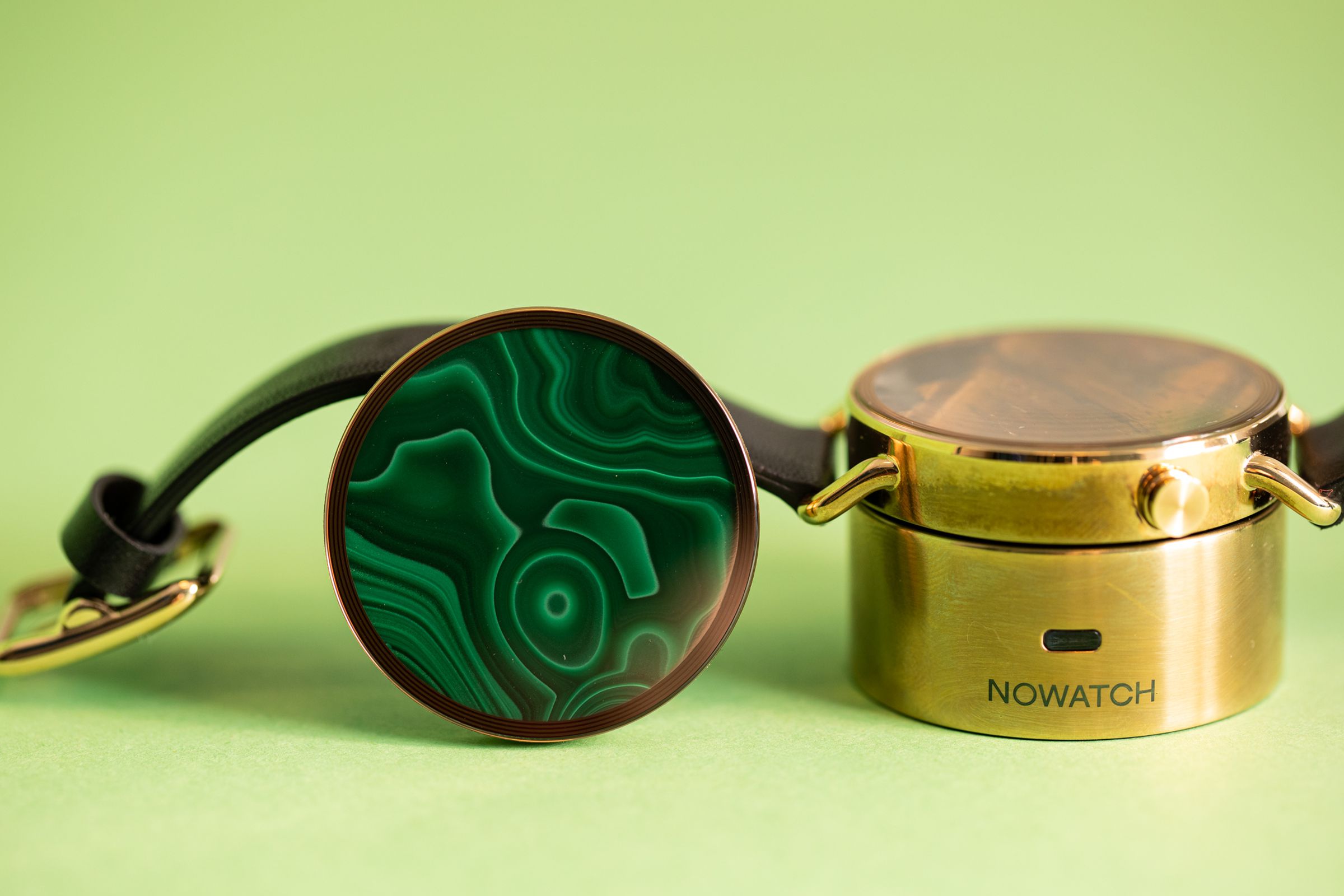 Nowatch device on its charger while an alternate agate disc is propped up next to it.