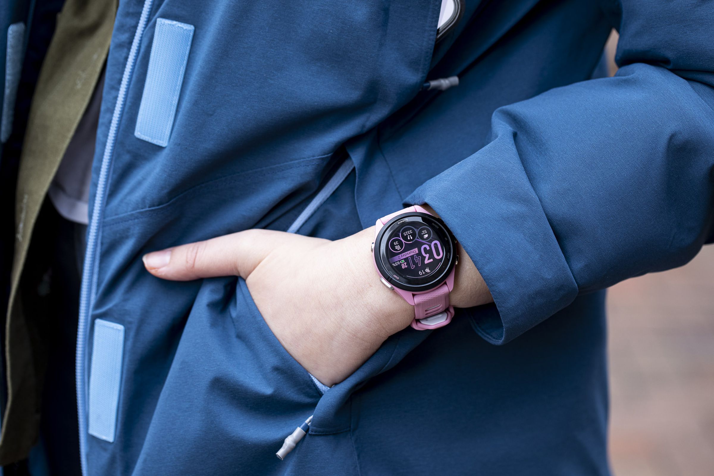 Close-up of the Garmin Forerunner 265S on the wrist of a person putting their hand into a jacket pocket.