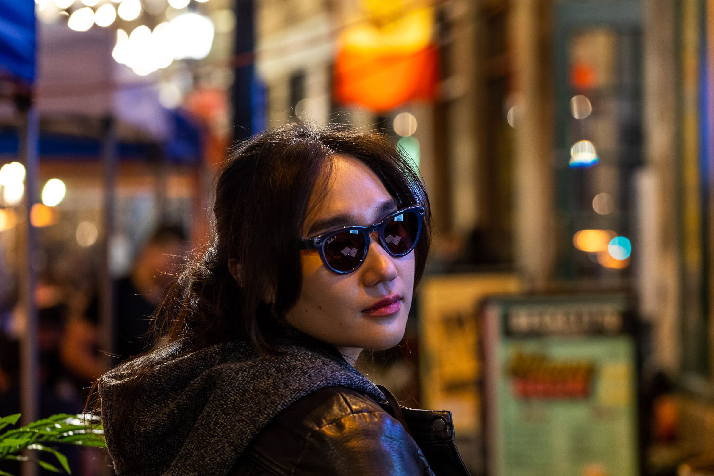 Person wearing leather jacket looking over their shoulder while wearing the Ray-Ban Meta Smart Glasses.