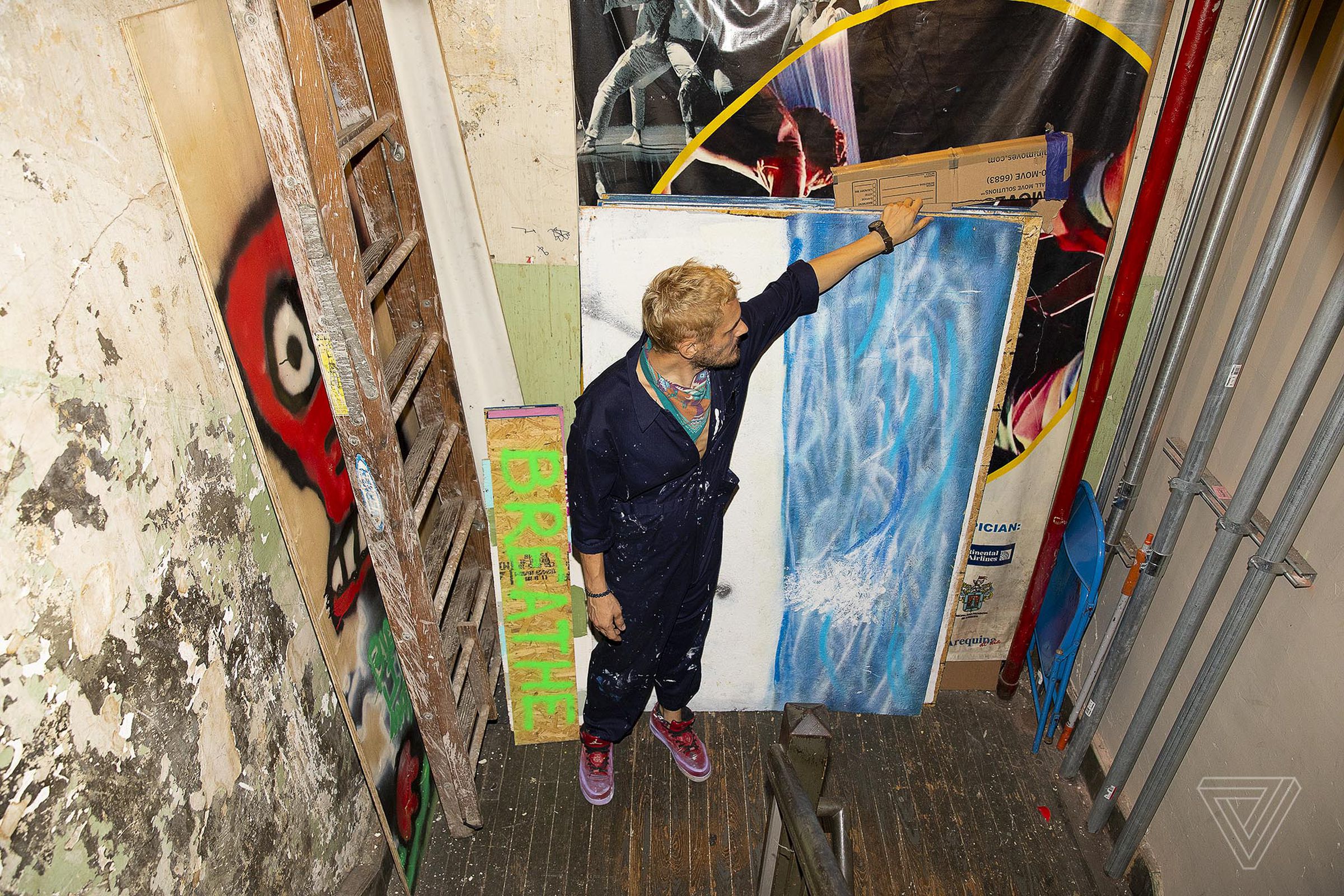 Trevor Croop in the staircase of his former studio space shows the many boards with work by various artists being stored there.
