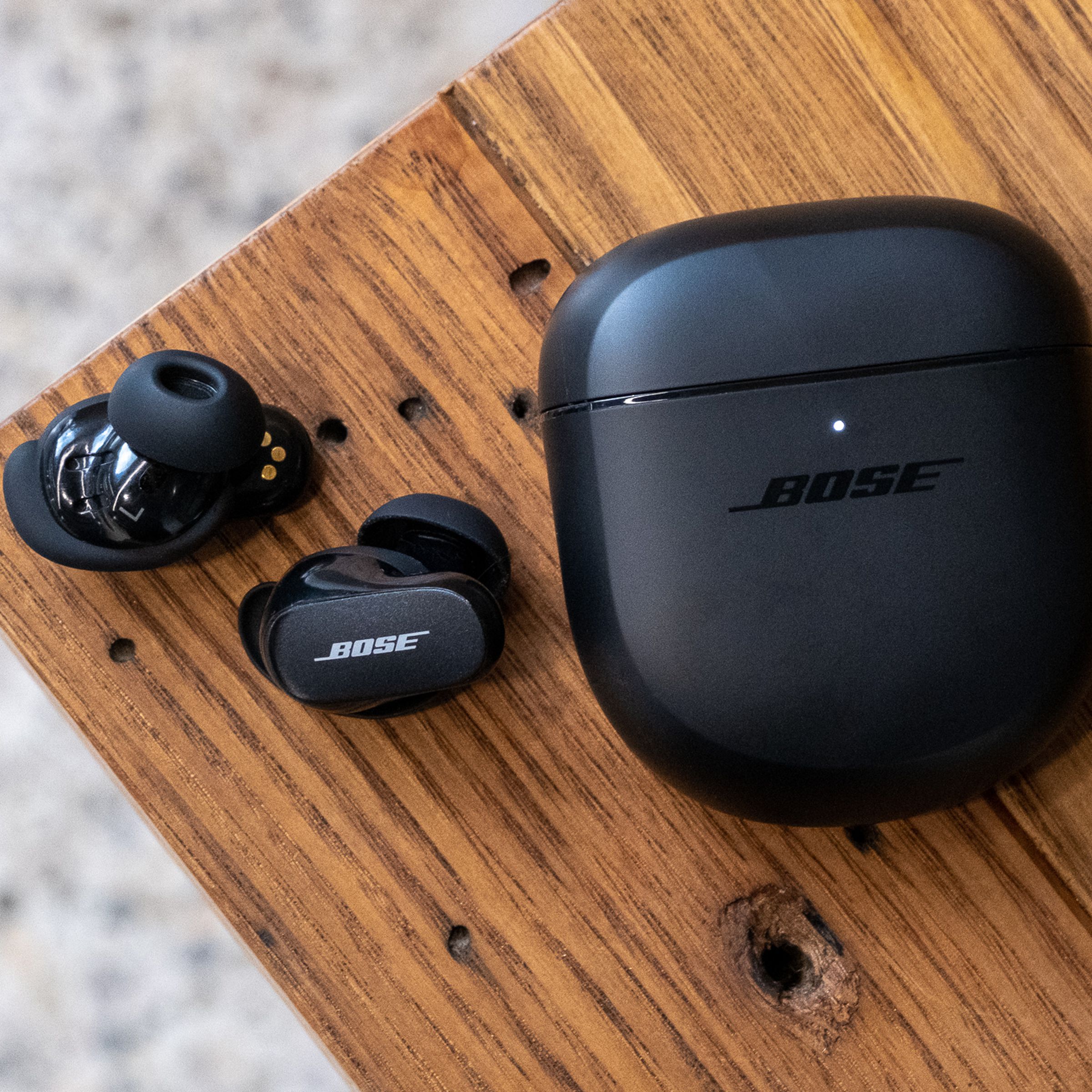 An overhead image of the Bose QuietComfort Earbuds II on a wood table.