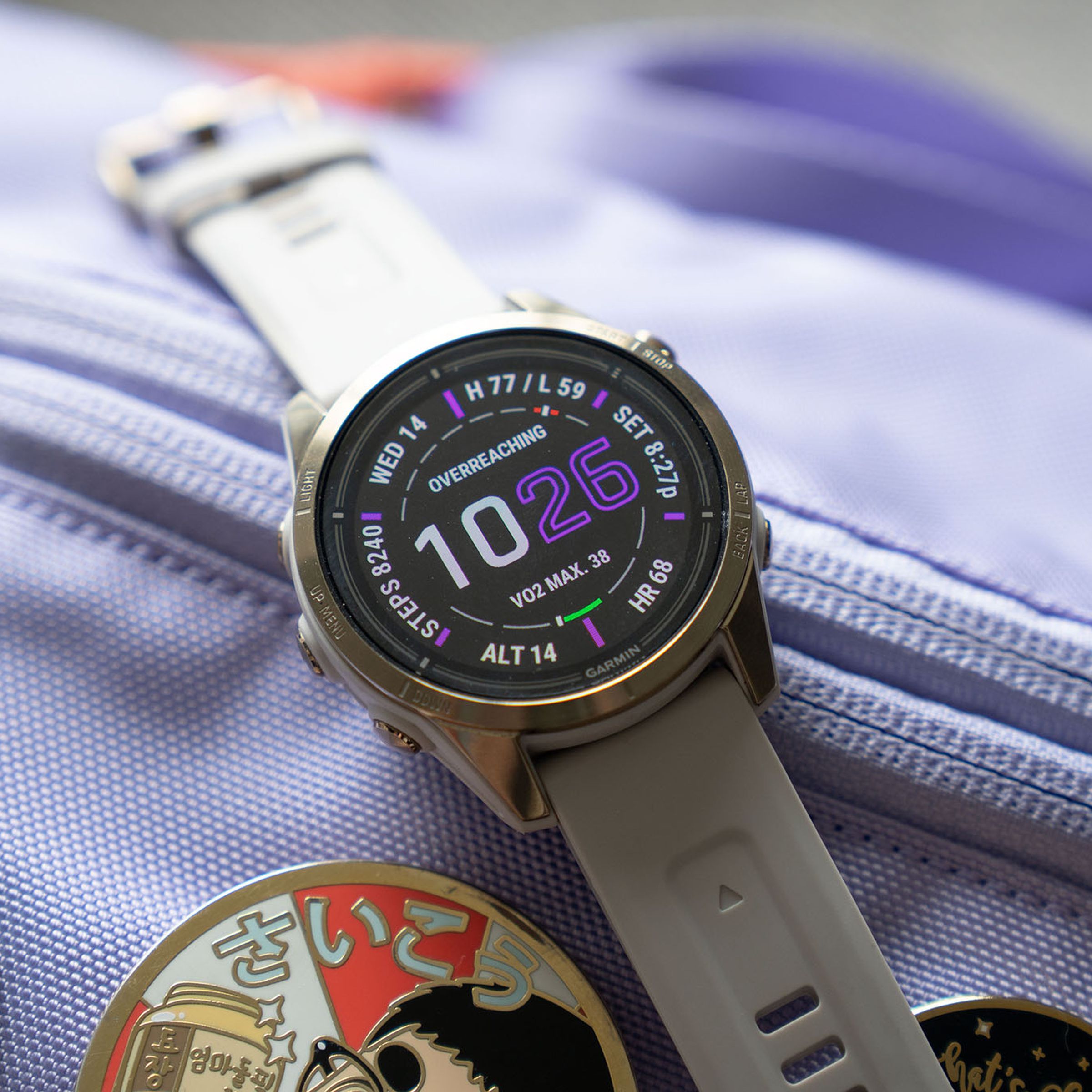 The 42mm Garmin Epix 2 Pro on top of a lavender bag with enamel pins.