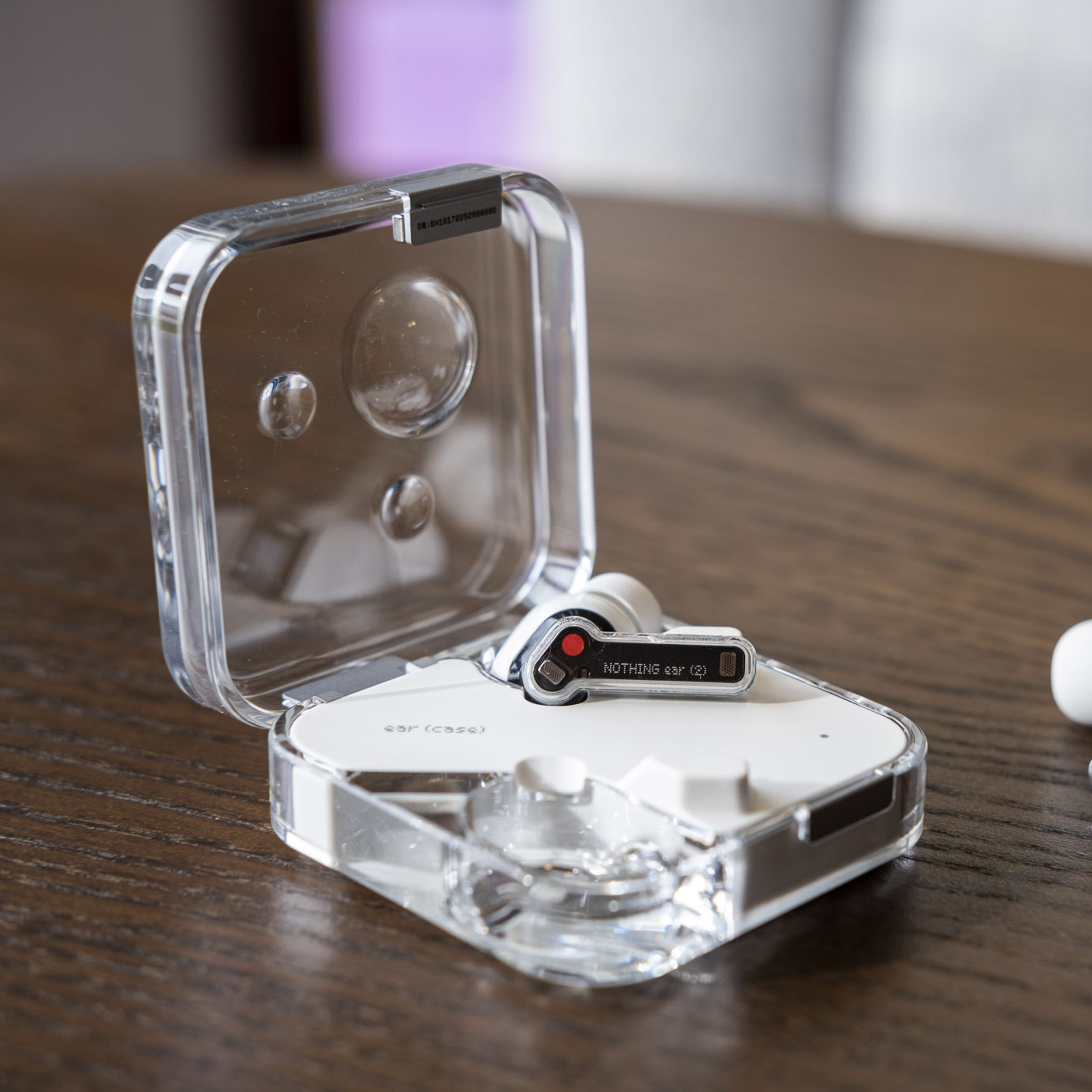 A photo of the Nothing Ear 2 earbuds with one earbud inside the charging case, and the other outside.