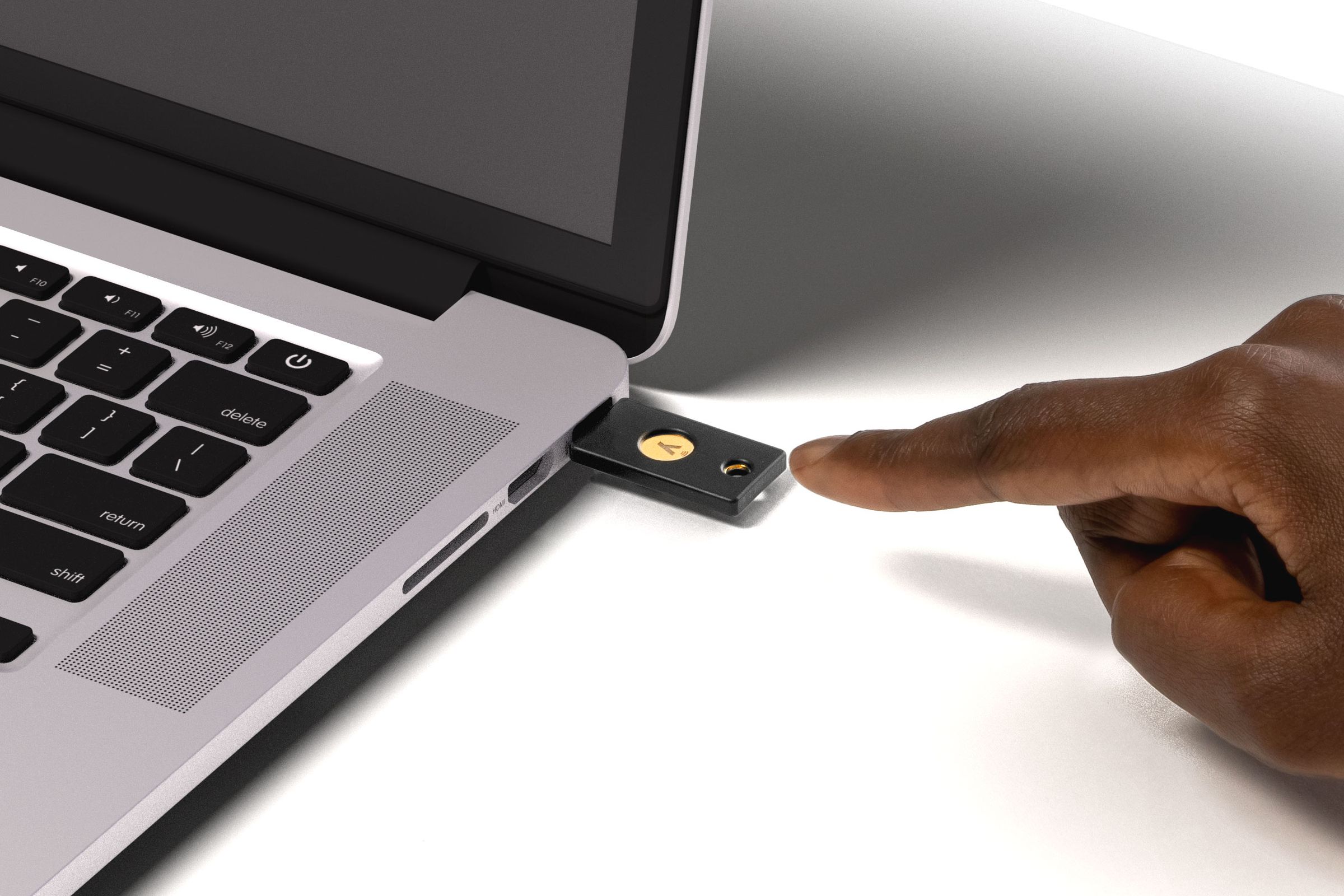 Someone using the YubiKey 5 NFC to access a laptop.