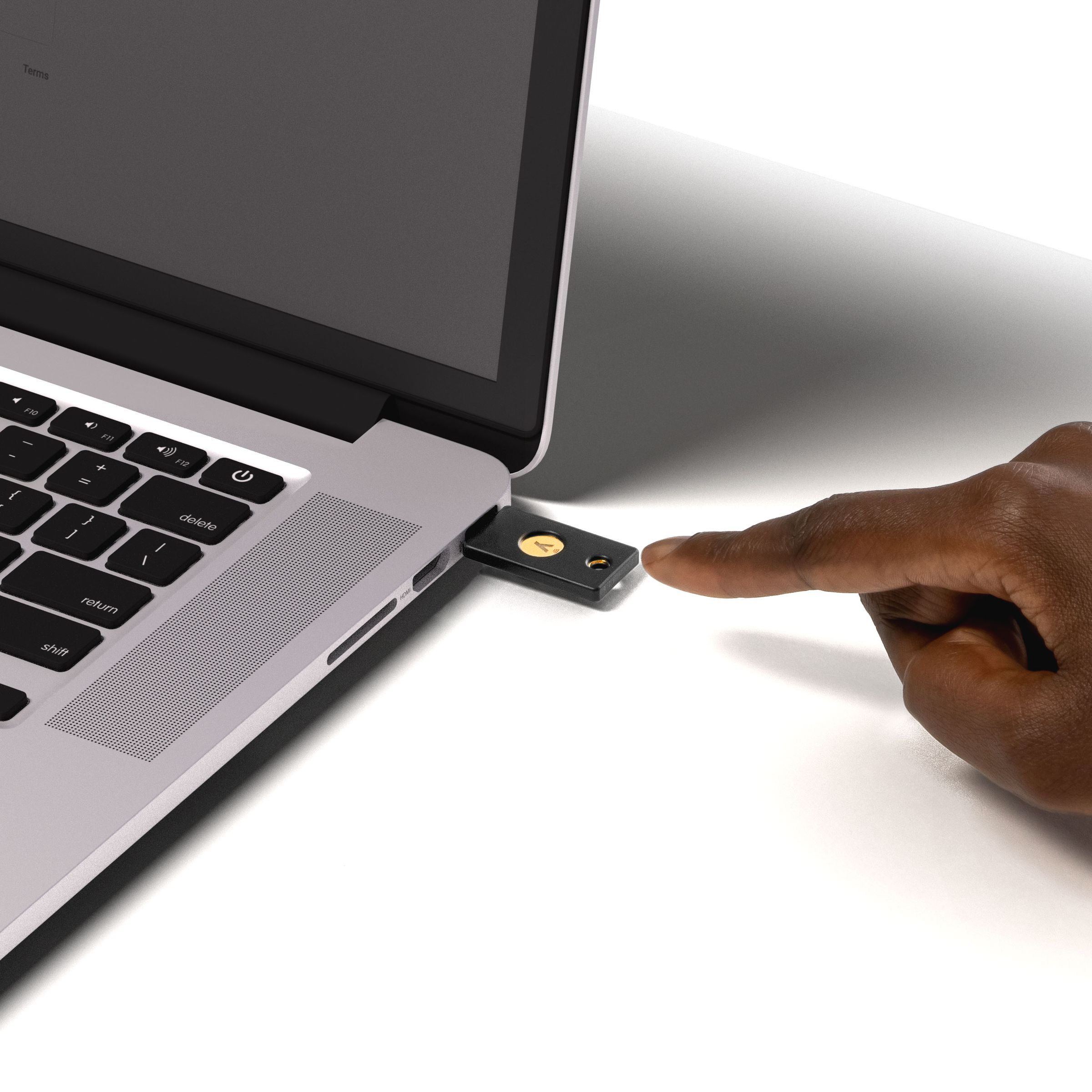 Someone using the YubiKey 5 NFC to access a laptop.