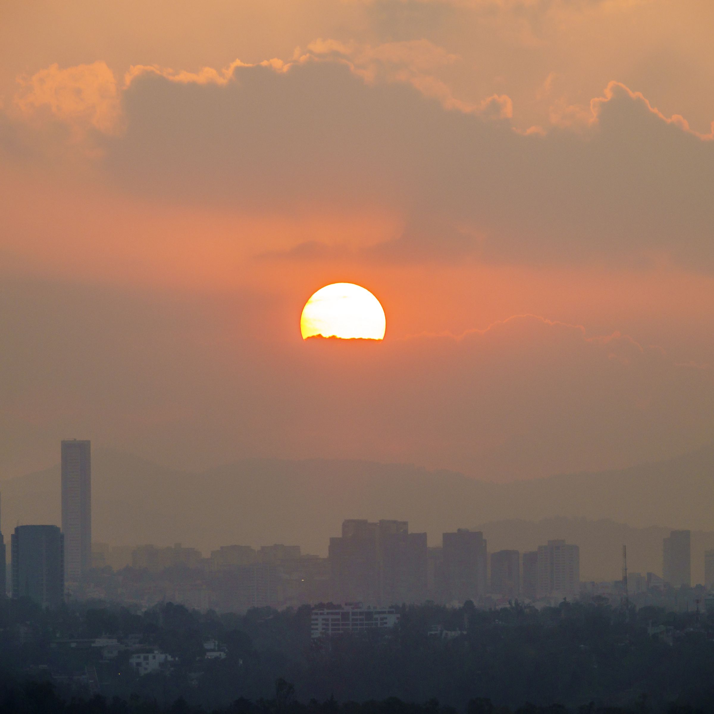 The city skyline at sunset, hazy with pollution.