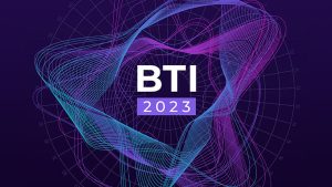 The image features the text "BTI 2023" centered amidst abstract, wavy lines in shades of blue and pink. The background is dark, with a faint radial grid pattern that enhances the sense of depth and motion.