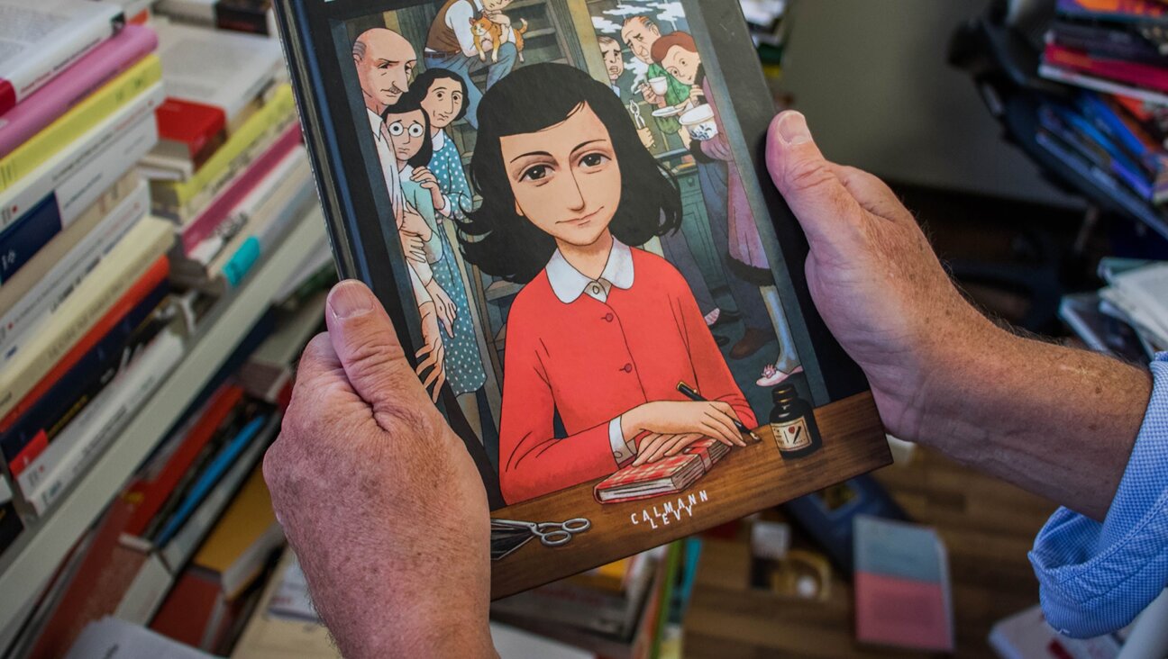 A man holds a copy of the graphic novel version of “The Diary of Anne Frank”, by Israeli writer-director Ari Folman and illustrator David Polonsky, in Paris Sept. 18, 2017. (Stringer/AFP via Getty Images)