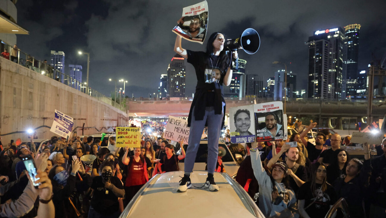 Einav Zangauker holds a sign identifying her son Matan Zangauker, one of the hostages taken captive by Hamas on Oct. 7, as she stands on the roof of a car during a demonstration by hostages' relatives and supporters in Tel Aviv on May 6, 2024. 