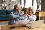 retired couple reviewing finances on a laptop